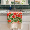 Floral towel with 'Poppies' text hanging over a kitchen sink.