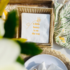 A cute bee-themed baby shower napkin is shown in a woven raffia napkin basket. The napkin features an image of a bee flying above text that reads "A Little Honey Is On The Way" - perfect for Winnie-the-Pooh Baby Showers.  