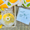 Cocktail with lemon garnish on a woven surface next to a paper cocktail napkin with a martini glass design and text that reads "A Tini Bit Older"