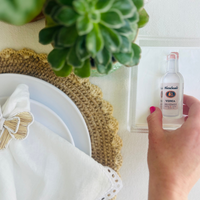 Hand picking up an acrylic napkin weight that's in the shape of a vodka bottle