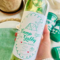 Hand holding a bottle that features a custom 'Camp Gabby' wine label for a nature-loving, outdoorsy bachelorette. 