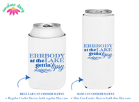 Two white can coolers, one for a slim can and one for a regular can, are shown against a white background. The can coolers feature a matching design with blue text that reads "Errbody at the Lake Gettin' Tipsy" 