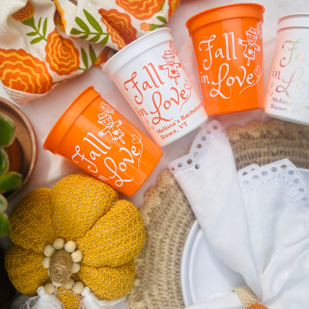 Fall In Love Autumn Theme Bachelorette Cups arced round a place setting and seen beside a pumpkin 