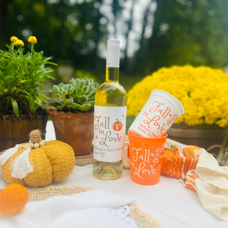 Fall in Love Bachelorette Wine Label and Cups showcased in a autumnal outdoor table setting