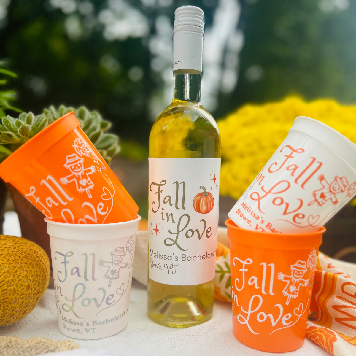 Fall in Love Customizable Stadium Cups for Fall Bachelorette stacked beside matching Sunshine Daisy "Fall In Love" wine label on bottle