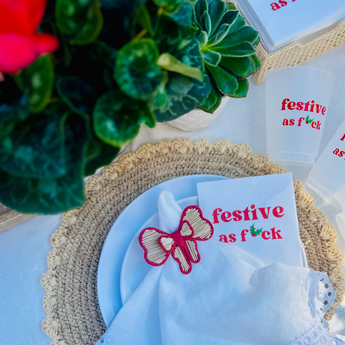 Napkin with 'festive as f*ck' text is featured on a decorative holiday table setting.