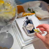 Hendrick's gin napkin weight on a stack of white cocktail napkins in a cocktail tray with a glass of gin and tonic in the background
