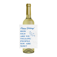 Wine bottle with a humorous birthday label on a white background. The wine label reads, "Happy Birthday! How old are we telling people you are now?"