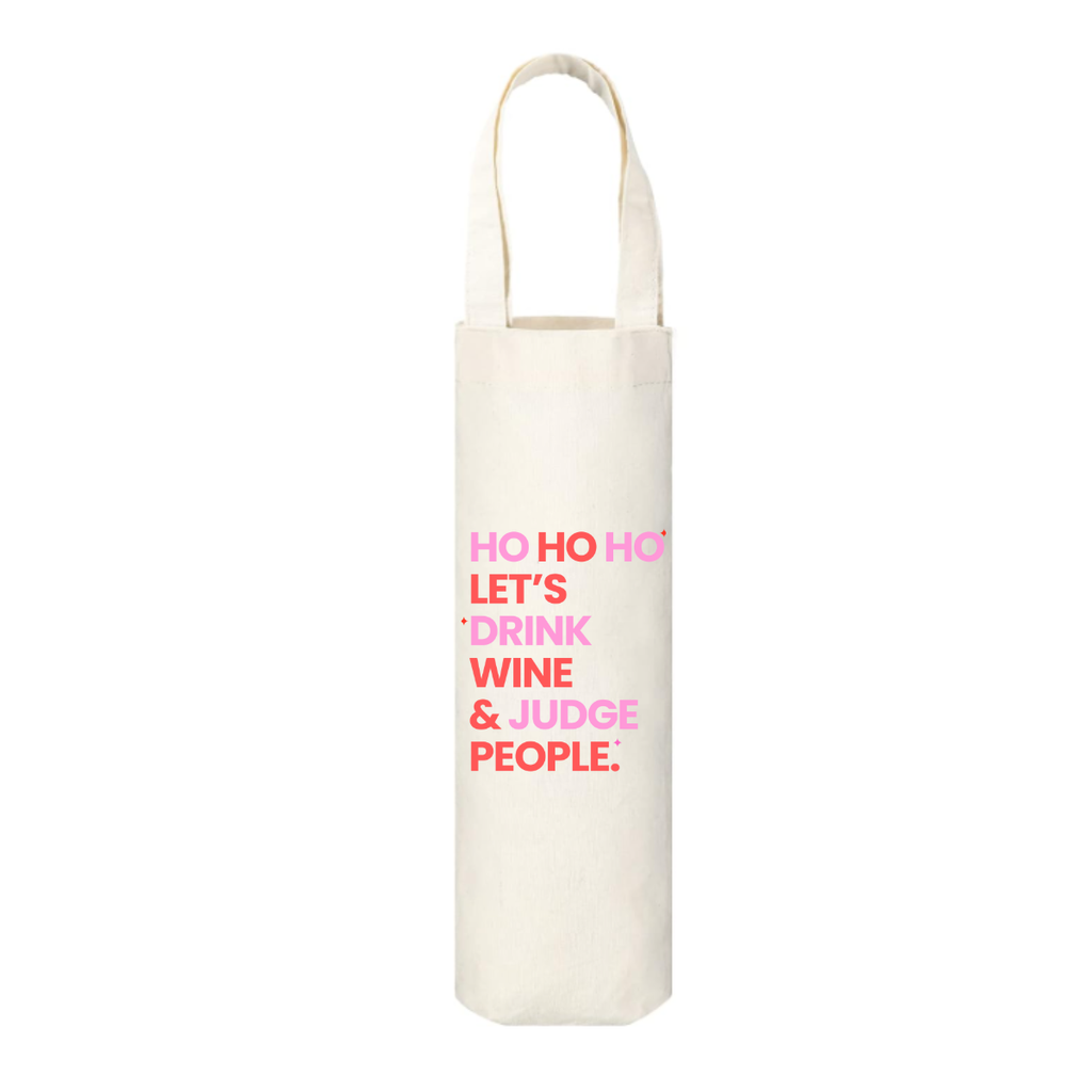 Canvas wine tote bag with pink and red text on a white background. The text says "Ho Ho Ho Let's Drink Wine & Judge People." A fun way to wrap any bottle of wine for the holidays, making the gift more laugh-out-loud, and memorable. 