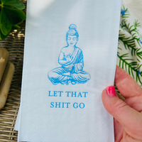 Hand holds up a white paper pindot guest towel with blue Buddha illustration and text that reads "Let That Shit Go"