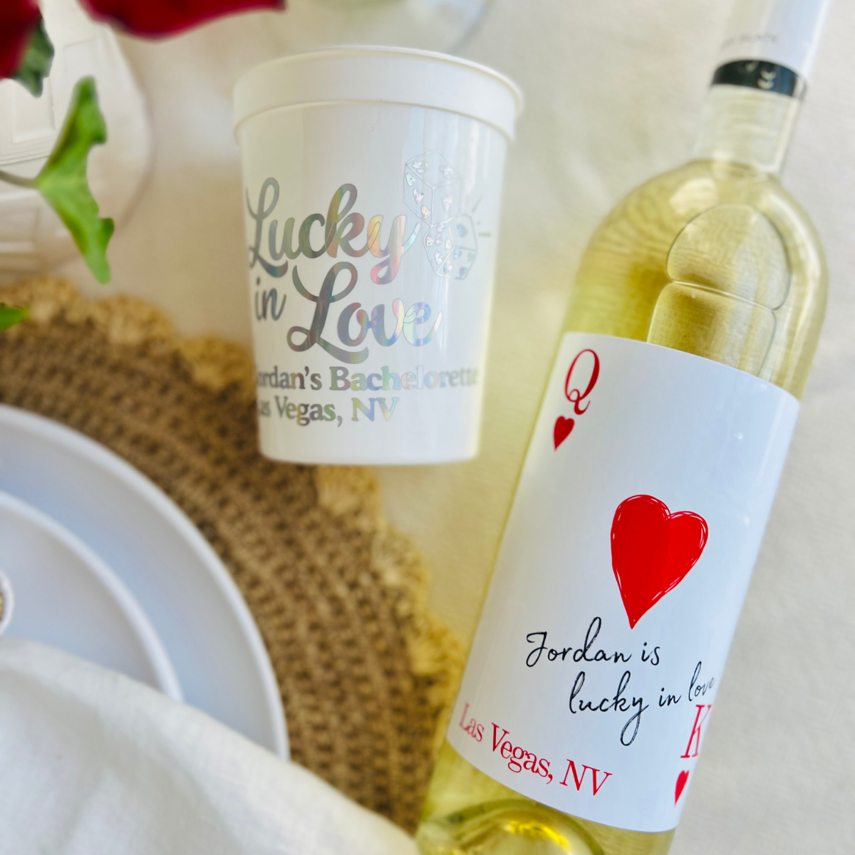 Bottle of white wine with a custom "Lucky in Love" wine label and a 'Lucky in Love' cup on a table.