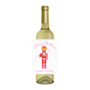 White wine bottle is shown with a fun Nutcracker-themed wine label. The wine label features a nutcracker design in bright colors with the text "Merry Christmas" arcing above the design, and a line of text that reads, "Honestly I feel nuts" below the image. The wine label is a fun way to dress up a wine bottle gift for the holidays.