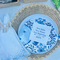 A napkin that features the text "New Baby New Home New Beginning" is shown on a decorative plate.