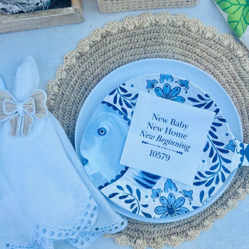 A napkin that features the text "New Baby New Home New Beginning" is shown on a decorative plate.