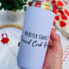White slim can cooler is held above a blurred table. The can cooler shows the back design with text that reads "Webster Family Annual Crab Bake"