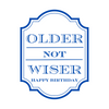 Close up of a white peel-and-stick wine label that features bold blue text that reads "Older Not Wiser - Happy Birthday."