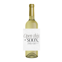 White wine bottle with a funny wine label for the holidays. The wine label features fun text that reads "Open this soon - there's a lot of family here." Perfect for gifting over the holidays, these hilarious, family-themed wine labels make great Secret Santa gifts, gag gifts, or fun party favors to enjoy with family.