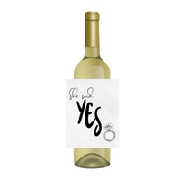 Wine bottle with a wine label reading 'She said... Yes' and an illustration of a diamond ring on a white background. Perfect for engagement parties, or as a fun gift to the newly engaged couple. 