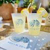 Two cups of lemonade with 'Shuck Yeah' branding on a table with decorative elements.
