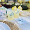 Two drinks with lemon slices in clear cups on a table with "Shuck Yeah" Oyster branded items.