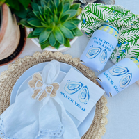 A cocktail napkin with matching can cooler sleeves features a design of shucked oyster shells and text that reads 'Shuck Yeah'