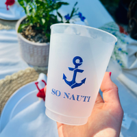 Clear plastic cup with blue anchor design and 'SO NAUTI' text held by a person outdoors.