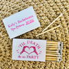Personalized bachelorette-themed matchbox set on a woven straw background. One closed white matchbox lid shows pink text reading 'Kelly's Bachelorette New Orleans, 2026,' and the open matchbox below shows wooden matches with a white lid printed with 'TIL DEATH do us PARTY' and a pink heart design.