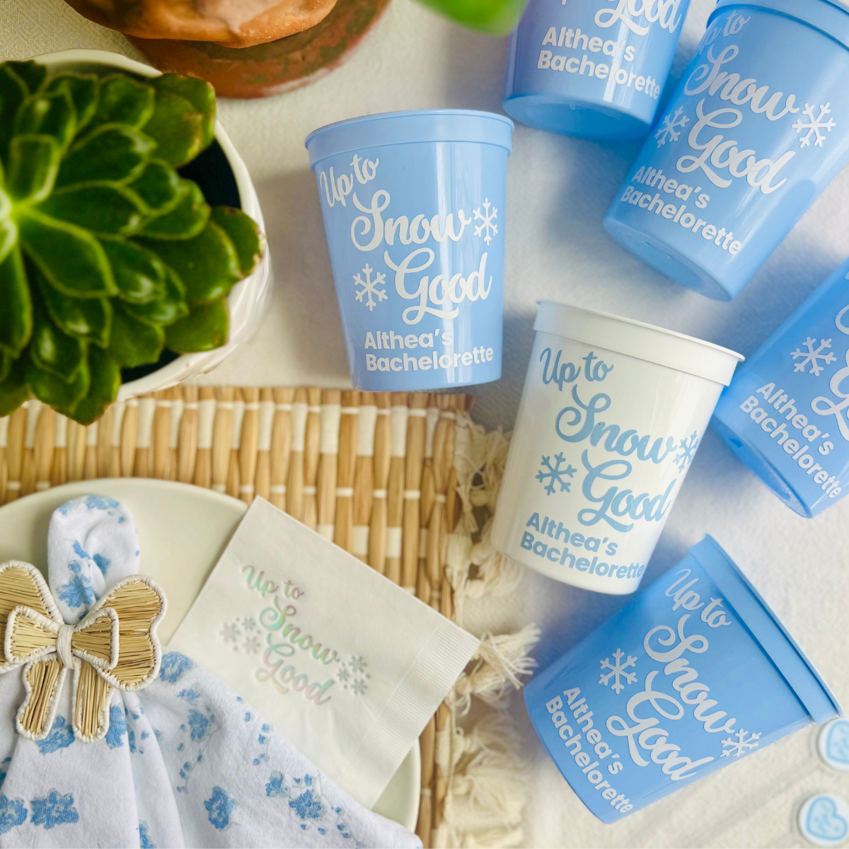 Blue and white bachelorette party cups with 'Up to Snow Good' text on a table with matching "Up To Snow Good" cups.
