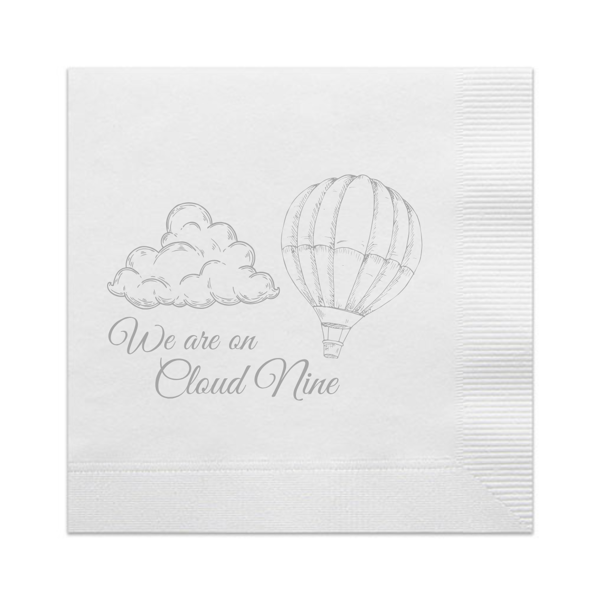 White paper cocktail napkin with a silver foil stamped design featuring script that reads "We Are On Cloud Nine." The script appear below a fluffy cloud and a floating hot air balloon. A perfect napkin for a gender reveal party or a "On Cloud Nine" baby shower. 