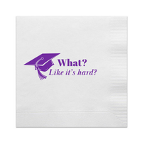 A pack of white cocktail paper beverage napkins with a purple foil stamped design that reads 'What? Like it's hard?' for graduation parties